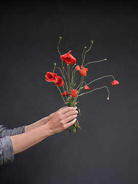 Frau h&auml;lt Mohnblumen in der Hand