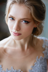 Young blonde bride woman in a light blue wedding dress, fashion beauty portrait in interior