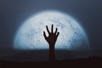 Halloween Concept, Hands out of the ground with a big moon background, creating an atmosphere of horror
