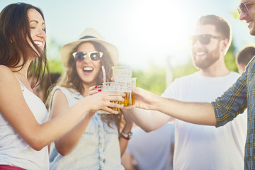 Friends cheering and drinking beer at outdoor party/music festival
