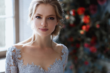 Young blonde bride woman in a light blue wedding dress, fashion beauty portrait in interior
