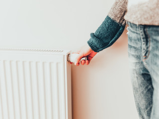 Woman adjusting temperature of home heater.