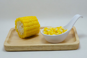 corn in a white spoon on wooden plate