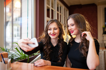Two beautiful girls do selfi and drink coffee