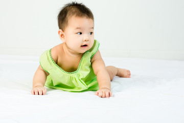 Portrait of adorable infant baby girl with saliva lying on the tummy on bed