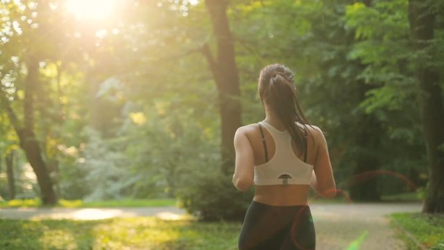 Back view of the young attractive woman running in the park at the early morning.