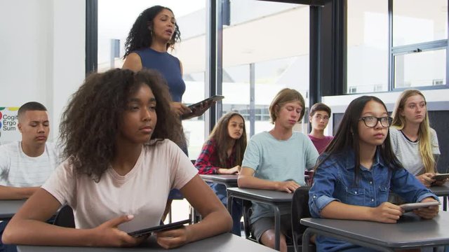 Teacher addressing pupils from the back of her high school class