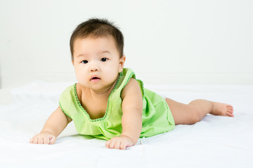 Portrait of adorable infant baby girl with saliva lying on the tummy on bed