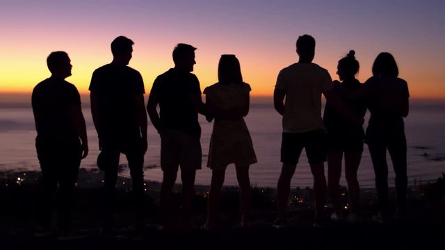 Group of young adults talking at sunset on a beach