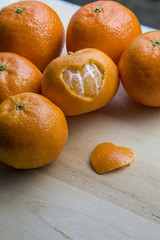 Several mandarins and peel in heart form are on the wooden background