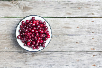 Cherry in a white bowl on a old wooden texture with rasty nails. Top view. Shallow depth of field.