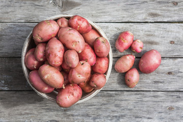 Fresh potato on a old wooden texture. Top view.