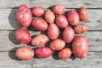 Fresh potato on a old wooden texture. Top view.