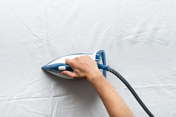 man ironing bed sheets
