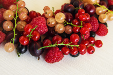 Mixed summer berries (raspberry, blackcurrant, redcurrant, white currant, gooseberry, cherry) on the white wooden background.