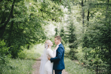 Beautiful married couple, bride hugs her groom in the park