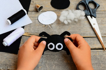 Small child holds a felt spider toy in his hand. Child made a Halloween felt spider crafts. Sewing workshop concept. Teaching a child to sew by hand