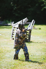 Paintball sport player in uniform and mask with gun outdoors