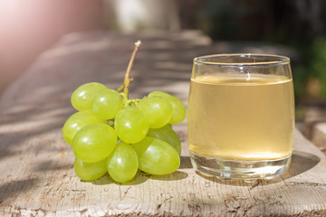 Bunch of green grapes and grape juice on wooden surface. Concept of healthy lifestyle. Culinary Concept