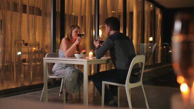 A couple on the first date in an elegant restaurant. A man tells smething about his companion about something