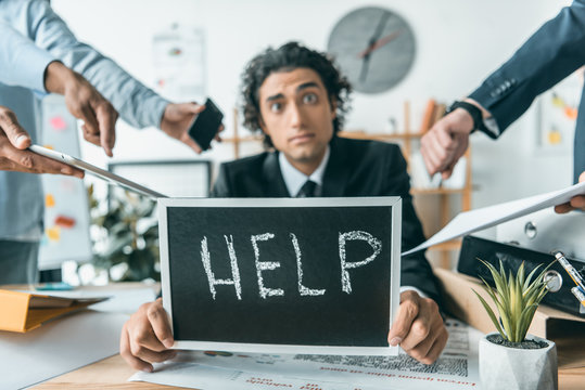 stressed businessman with help blackboard having troubles with deadline with colleagues standing near by
