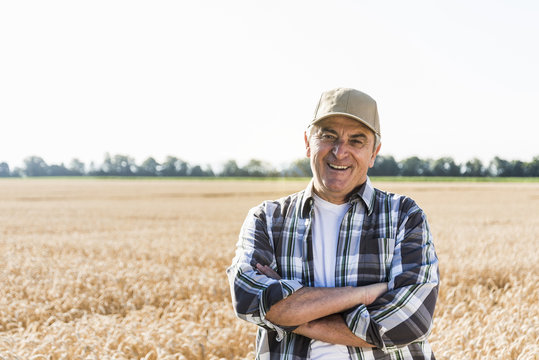 Portrait of laughing senior farmer standing in front of a field