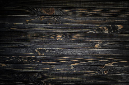 Black wood striped texture with vignette. A wooden surface lit by a spot of light