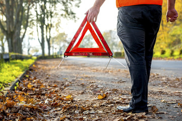 Legs of man with warning triangle at roadside
