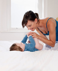 Mother smiling at baby lying on bed