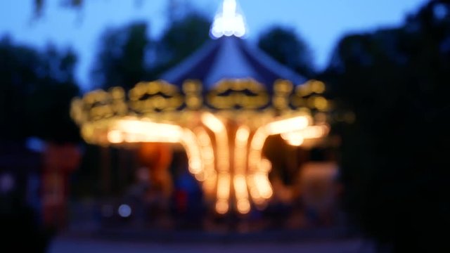Beautiful Dark Park Background. French Carousel Is Spinning And Glowing With Lights In Twilight Вusk. Blurred Carousel. Bokeh Lights Glowing Carousel