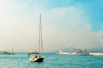 Obraz premium Moored yacht and a fishing trawler in the harbor of a small town called Postira - Croatia, island Brac