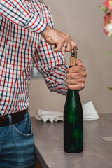 Sommelier Opening a wine bottle with corkscrew in a bar