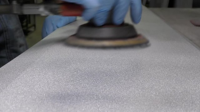 Man preparing metal panel with an orbital sander