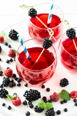 Fruit tea with blackberry, blueberry and raspberry decorated mint leaves on wooden desk. Selective focus