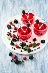 Fruit tea with blackberry, blueberry and raspberry decorated mint leaves on wooden desk. Selective focus