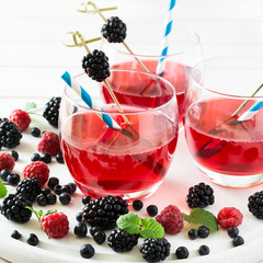 Fruit tea with blackberry, blueberry and raspberry decorated mint leaves on wooden desk. Selective focus