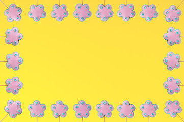 Frame of homemade gingerbreads in the form of pink flowers on the yellow background. Picture for a menu or a confectionery catalog. Invitation or greeting card.