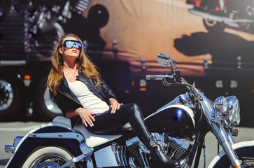 Naklejka na ściany i meble Casual beautiful woman sits on a big tourist motorcycle on the street bright smile on a sunny day