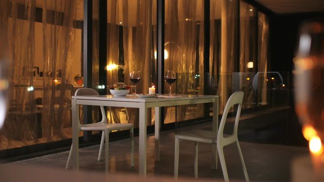 An empty restaurant is ready for a romantic date. On the table are glasses of wine and food