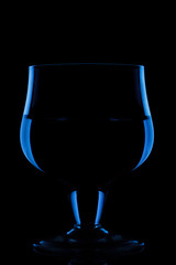 Blue silhouette of a glass with liquid on a black background