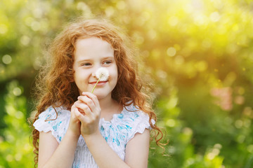 Little curly girl blowing dandelion.