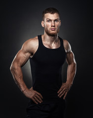 Fototapeta na wymiar Portrait of a muscular male model against black background