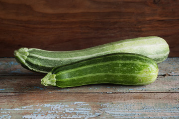 two zucchini on an old wooden table.