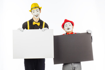 Two funny mimes holding a white blank on a white background.