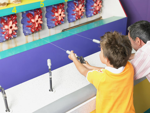 Father And Son Playing On Fairground Stall