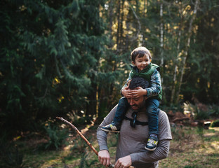 Young dad enjoying hike with happy little boy on his shoulders