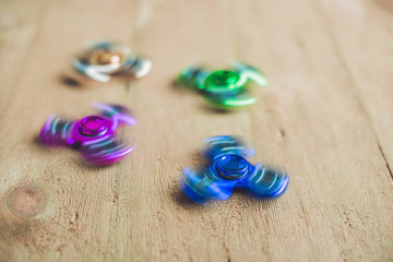 Colored fidget spinners stress relieving toy on wooden background
