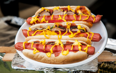 Three hot dogs with ketchup and mustard in a white plate