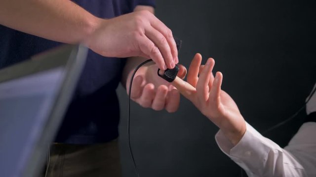 An operator attaches an electrode on a subject s finger. 