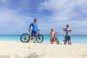 father with little son and daughter biking on beach